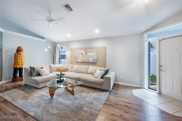 living area featuring lofted ceiling, wood finished floors, visible vents, and baseboards