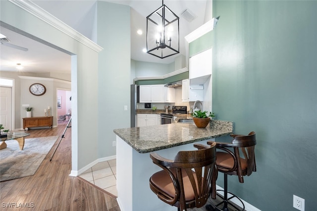 kitchen featuring white cabinetry, a sink, visible vents, stainless steel range with electric cooktop, and a towering ceiling
