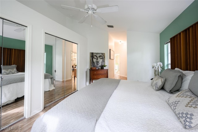 bedroom with connected bathroom, a ceiling fan, visible vents, and wood finished floors