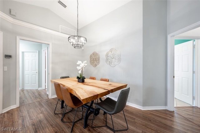dining area with lofted ceiling, dark wood-type flooring, a chandelier, and baseboards