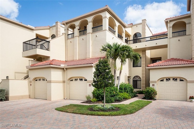 7048 Pelican Bay Blvd Unit C104, Naples, FL 34108 - mediterranean / spanish house with a garage, stucco siding, decorative driveway, a balcony, and a tiled roof