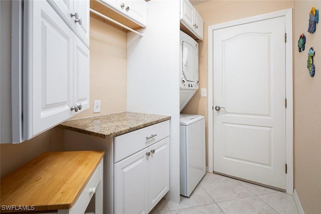 7048 Pelican Bay Blvd Unit C104, Naples, FL 34108 - washroom featuring stacked washing maching and dryer, light tile patterned floors, baseboards, and cabinet space