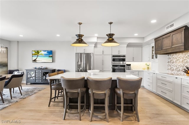 14250 Royal Harbour Ct Unit 913, Fort Myers, FL 33908 - kitchen with appliances with stainless steel finishes, a kitchen island, light countertops, a kitchen breakfast bar, and light wood finished floors