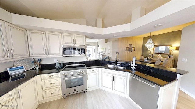 6805 Satinleaf Rd S Unit 201, Naples, FL 34109 - kitchen with a sink, appliances with stainless steel finishes, dark countertops, light wood-style floors, and a peninsula