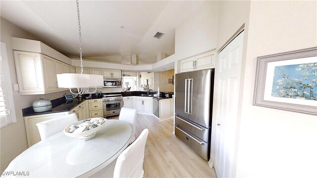 6805 Satinleaf Rd S Unit 201, Naples, FL 34109 - kitchen with lofted ceiling, a sink, dark countertops, light wood-style floors, and high quality appliances