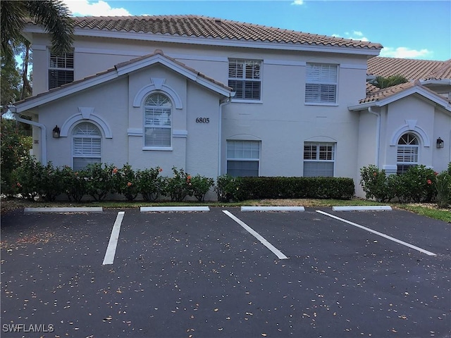 6805 Satinleaf Rd S Unit 201, Naples, FL 34109 - view of front facade with stucco siding, a tiled roof, and uncovered parking
