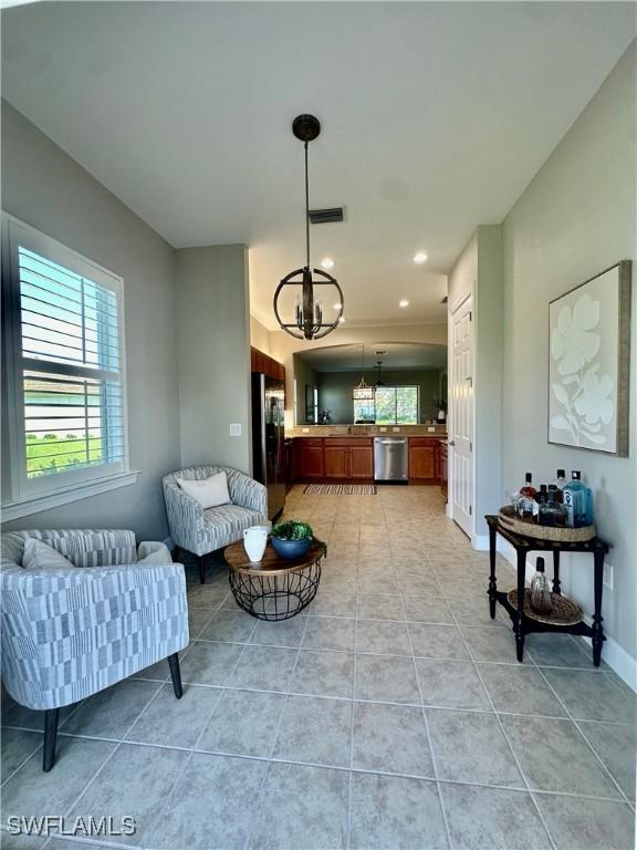 living room with a chandelier, visible vents, light tile patterned floors, and baseboards