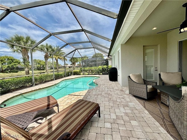 outdoor pool featuring a patio, glass enclosure, and a ceiling fan