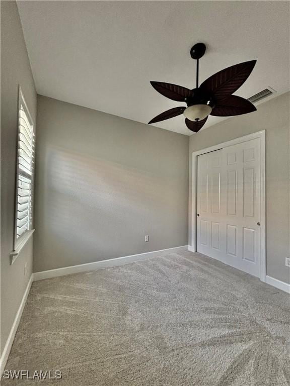 unfurnished bedroom featuring visible vents, ceiling fan, a closet, baseboards, and carpet