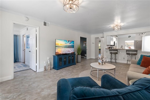 living room featuring baseboards, visible vents, an inviting chandelier, and crown molding