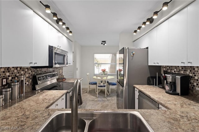 kitchen featuring white cabinets, light stone counters, stainless steel appliances, and tasteful backsplash