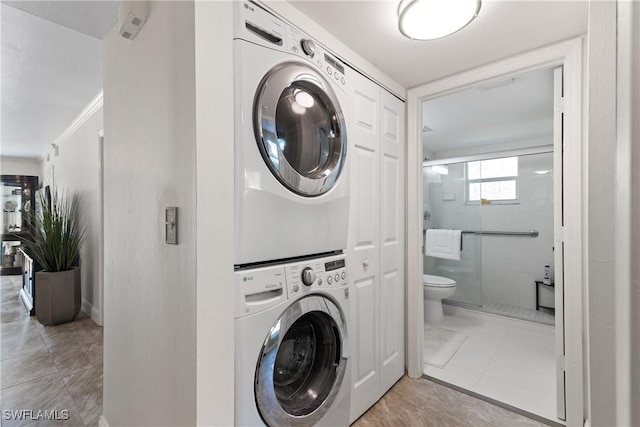 laundry area featuring light tile patterned floors, stacked washer / drying machine, and laundry area