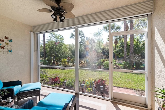 sunroom with a textured ceiling, a textured wall, and a ceiling fan
