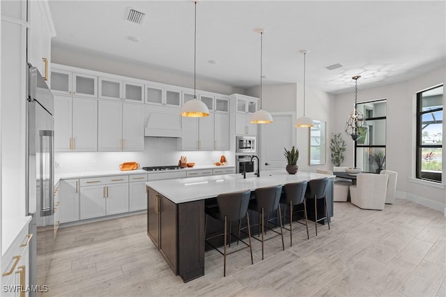 16198 Verilyn Cir, Naples, FL 34110 - kitchen featuring light wood-style floors, a kitchen bar, light countertops, and white cabinets