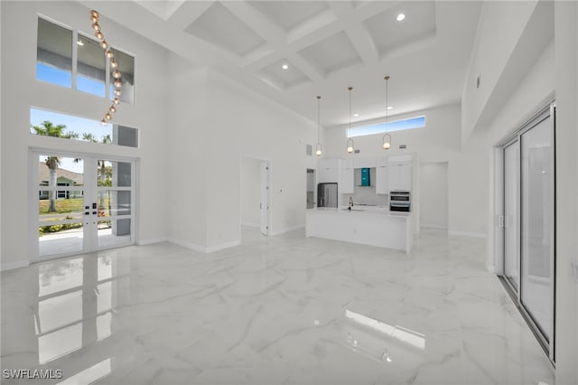 unfurnished living room featuring beamed ceiling, a towering ceiling, coffered ceiling, and baseboards