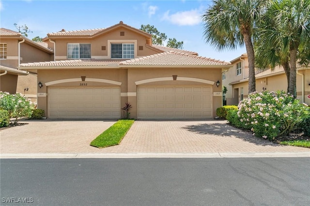 view of front of property featuring a tiled roof, decorative driveway, and stucco siding