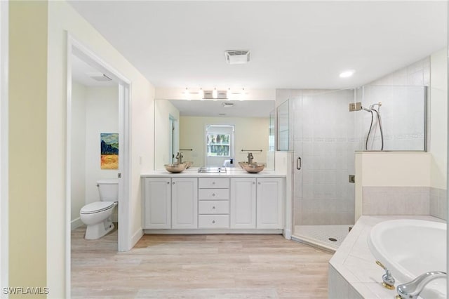 full bath with visible vents, double vanity, wood finished floors, a bath, and a shower stall