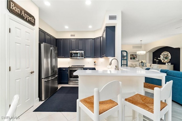 kitchen with stainless steel appliances, open floor plan, a peninsula, a kitchen bar, and visible vents