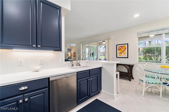 kitchen with stainless steel dishwasher, decorative backsplash, blue cabinets, a sink, and light tile patterned floors