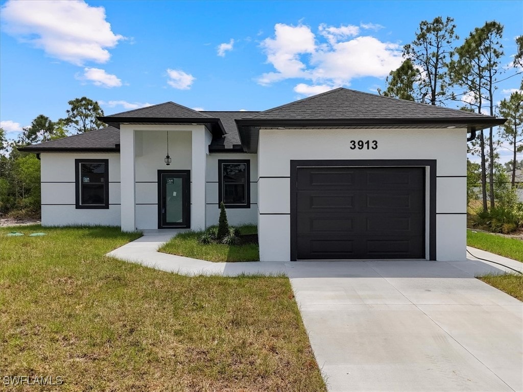 3913 4th St SW, Lehigh Acres, FL 33976 - prairie-style home featuring a front yard, a garage, a shingled roof, concrete driveway, and stucco siding