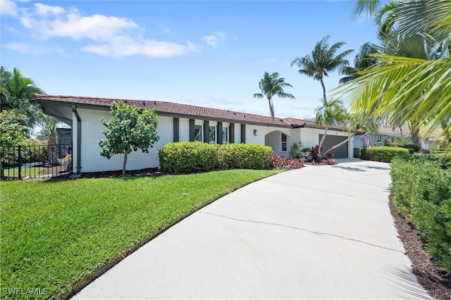 view of front of home featuring stucco siding, fence, a garage, a front yard, and concrete driveway