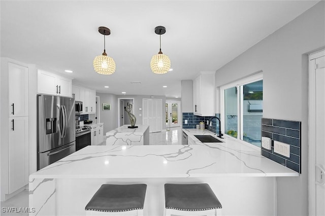 kitchen featuring tasteful backsplash, white cabinets, a sink, appliances with stainless steel finishes, and light stone countertops