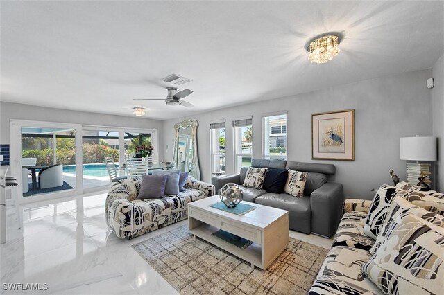 living area featuring marble finish floor, visible vents, and ceiling fan with notable chandelier