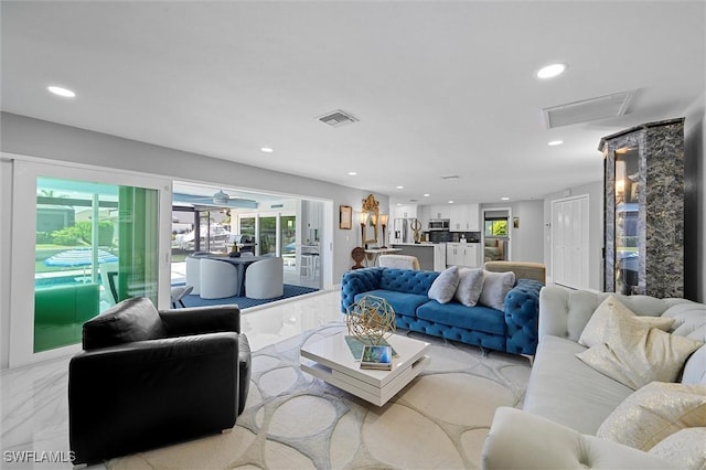 living area with attic access, visible vents, recessed lighting, and marble finish floor