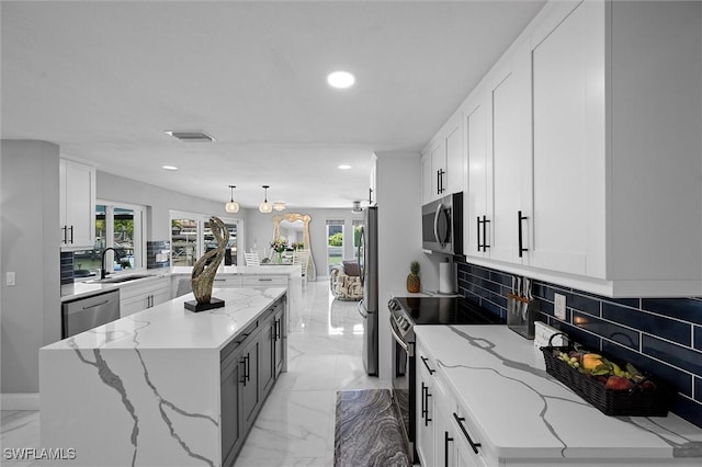 kitchen with marble finish floor, a sink, a peninsula, and stainless steel appliances