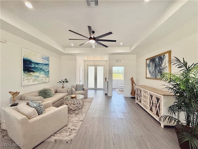 living area with visible vents, a raised ceiling, french doors, and recessed lighting