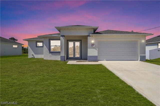 prairie-style house featuring a garage, a yard, stucco siding, and concrete driveway