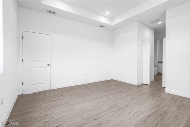 unfurnished room featuring visible vents, baseboards, wood finished floors, and a tray ceiling
