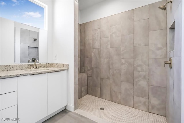 full bath featuring a tile shower and vanity