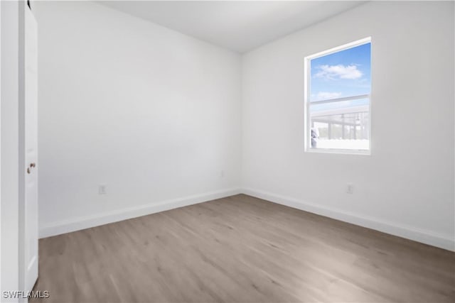 unfurnished room featuring baseboards and light wood-type flooring