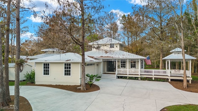 view of front facade with a gazebo, an attached garage, driveway, and metal roof