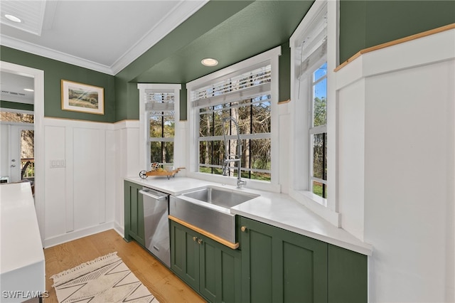 kitchen with green cabinetry, light wood finished floors, a wainscoted wall, stainless steel dishwasher, and ornamental molding