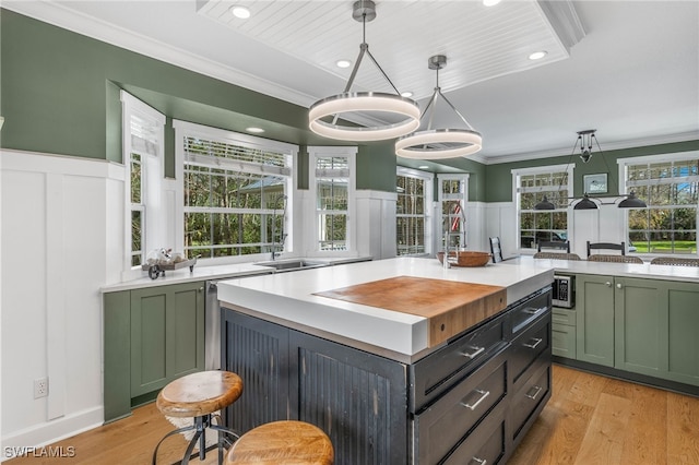 kitchen featuring ornamental molding, green cabinetry, stainless steel microwave, and a decorative wall