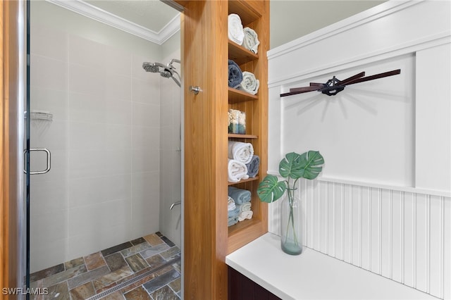 bathroom featuring stone finish flooring, a shower stall, and ornamental molding