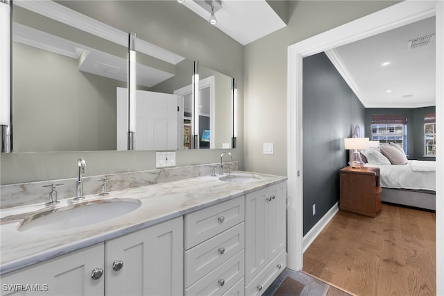 ensuite bathroom with a sink, ornamental molding, ensuite bath, and double vanity