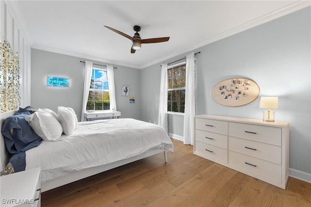 bedroom with light wood-type flooring, ornamental molding, baseboards, and a ceiling fan