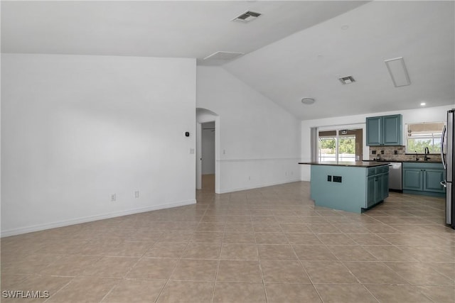 1227 Damen St E, Lehigh Acres, FL 33974 - kitchen with dark countertops, open floor plan, a center island, vaulted ceiling, and arched walkways