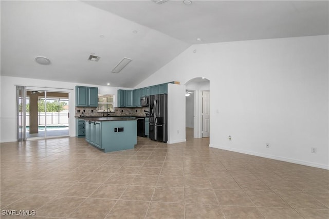 1227 Damen St E, Lehigh Acres, FL 33974 - kitchen featuring freestanding refrigerator, dark countertops, arched walkways, blue cabinetry, and vaulted ceiling
