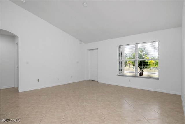 1227 Damen St E, Lehigh Acres, FL 33974 - empty room with arched walkways, light tile patterned flooring, baseboards, and high vaulted ceiling