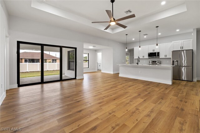 2706 39th St W, Lehigh Acres, FL 33971 - unfurnished living room featuring a sink, a raised ceiling, visible vents, recessed lighting, and light wood finished floors