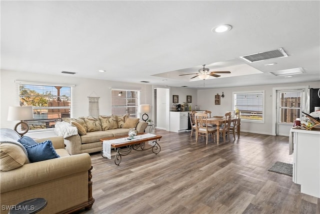 living room featuring visible vents, a ceiling fan, wood finished floors, and a tray ceiling