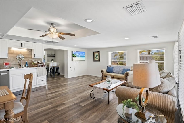 living area with baseboards, visible vents, dark wood-style floors, and ceiling fan