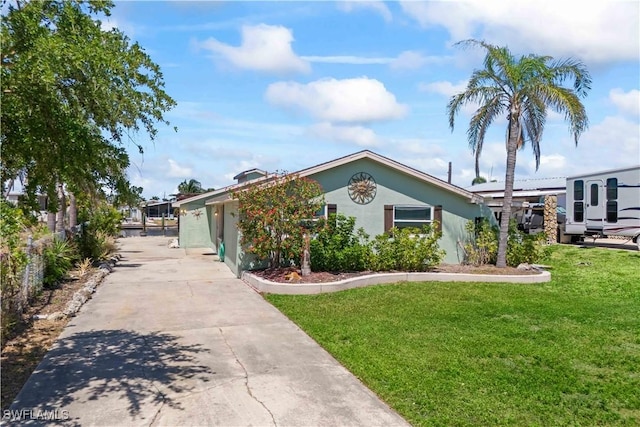 view of front of home featuring stucco siding, concrete driveway, and a front yard
