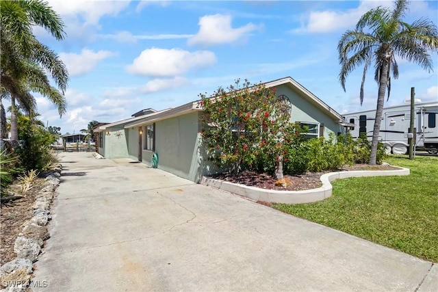 view of home's exterior with concrete driveway, a yard, and stucco siding