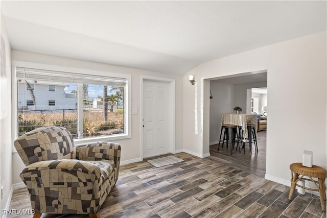 living area featuring baseboards, wood finished floors, and lofted ceiling