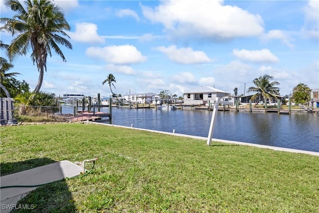 dock area featuring a yard, a water view, fence, and boat lift